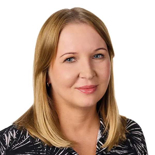 Kobieta o blond włosach, niebieskich oczach i jasnej karnacji, ubrana w czarną bluzkę w biały wzór.