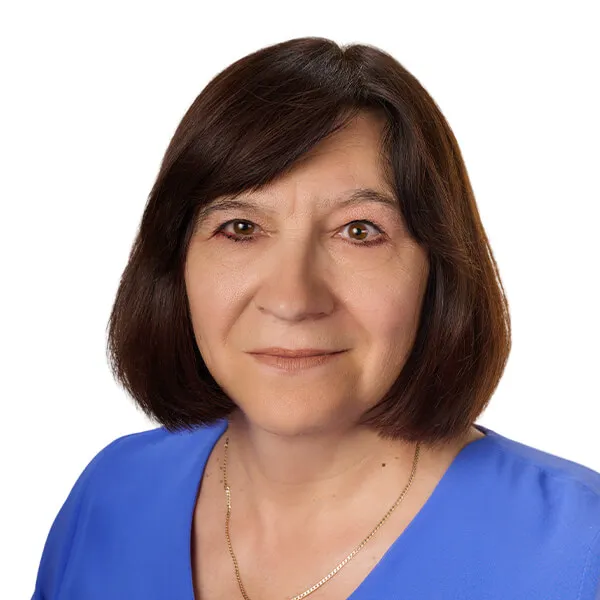 Kobieta o ciemnych włosach do ramion, ubrana w niebieską bluzkę i złoty łańcuszek.