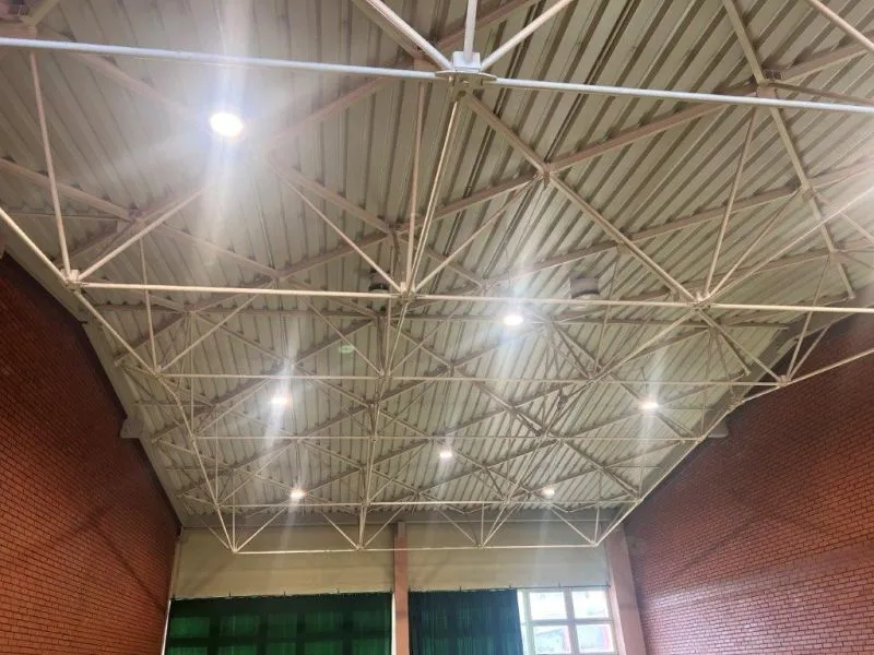 Suwnicowa konstrukcja dachowa hali z metalowymi kratownicami i oświetleniem.