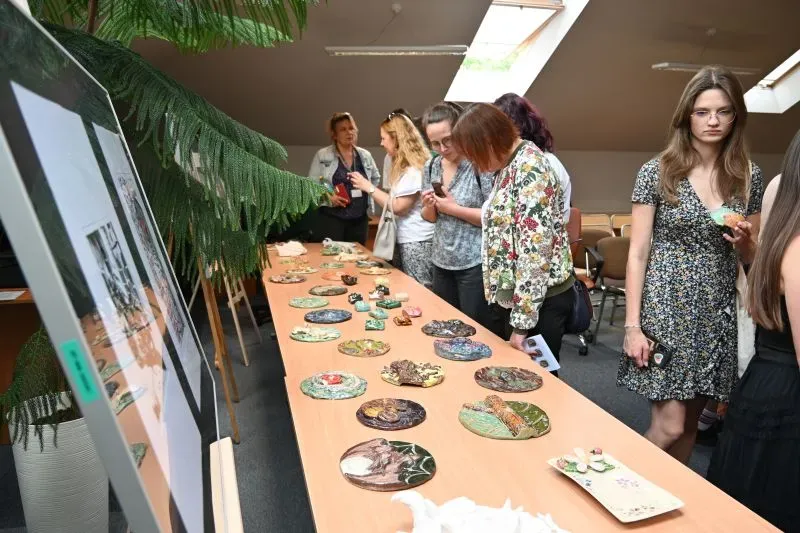 Kobiety oglądają ręcznie wykonane ceramiczne ozdoby ułożone na stole.