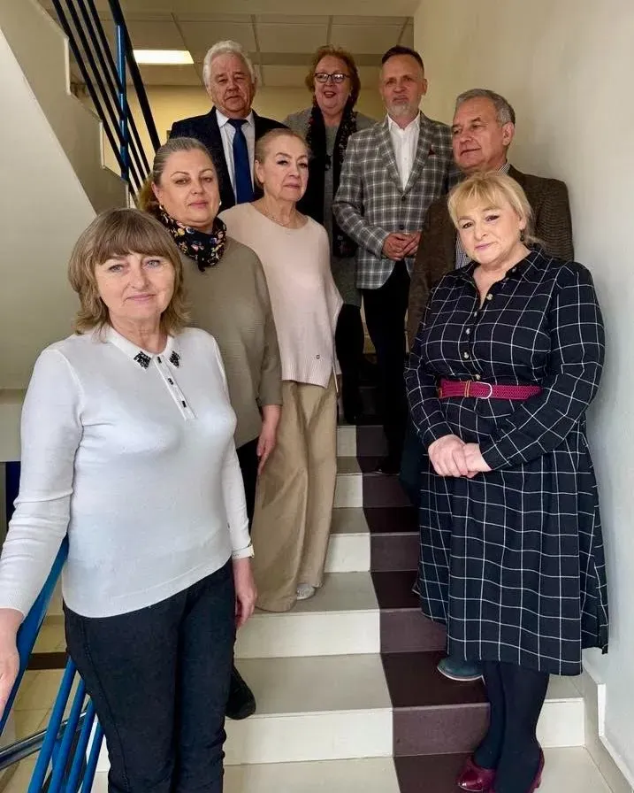 Osiem osób stoi na schodach w korytarzu.